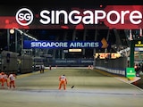 Los alguaciles limpian la pista de agua superficial después de que la lluvia retrasara el inicio del Gran Premio de Singapur de F1.
