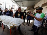 Personas llevan el cuerpo de uno de los trabajadores extranjeros asesinados, ayer en Rafah, Gaza.