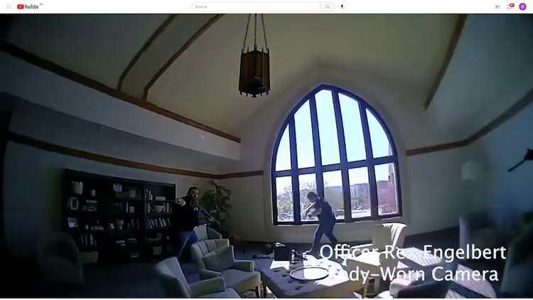 Dos policías se acercan a la víctima, ya tendida en el suelo.