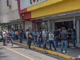 Personas esperan en largas filas para poder ingresar a una tienda de venta de artículos por crédito