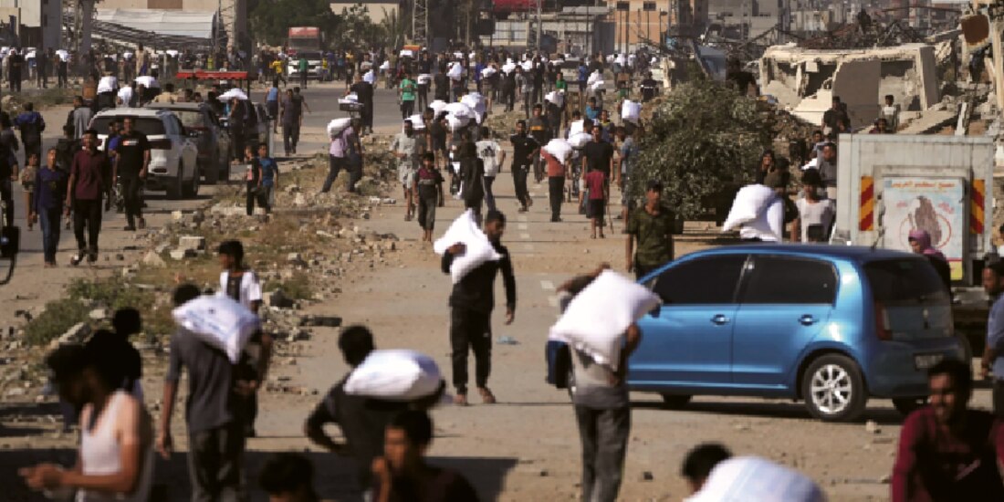 Palestinos cargan sacos de harina tras asaltar un almacén del Programa Mundial de Alimentos de la ONU en Zawaida, en el centro de Gaza, ayer.
