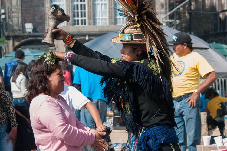 Personas que visitan el zócalo capitalino aprovechan a los curanderos que se encuentran a un costado de la catedral metropolitana para realizarse una limpia.