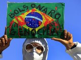 En esta fotografía de archivo del 26 de mayo de 2021, un manifestante sostiene una imagen de la bandera brasileña cubierta de sangre falsa y la frase portuguesa "Genocidio de Bolsonaro" durante una protesta antigubernamental de los sindicatos contra las políticas del presidente Jair Bolsonaro para combatir la pandemia de COVID-19. en Brasilia, Brasil