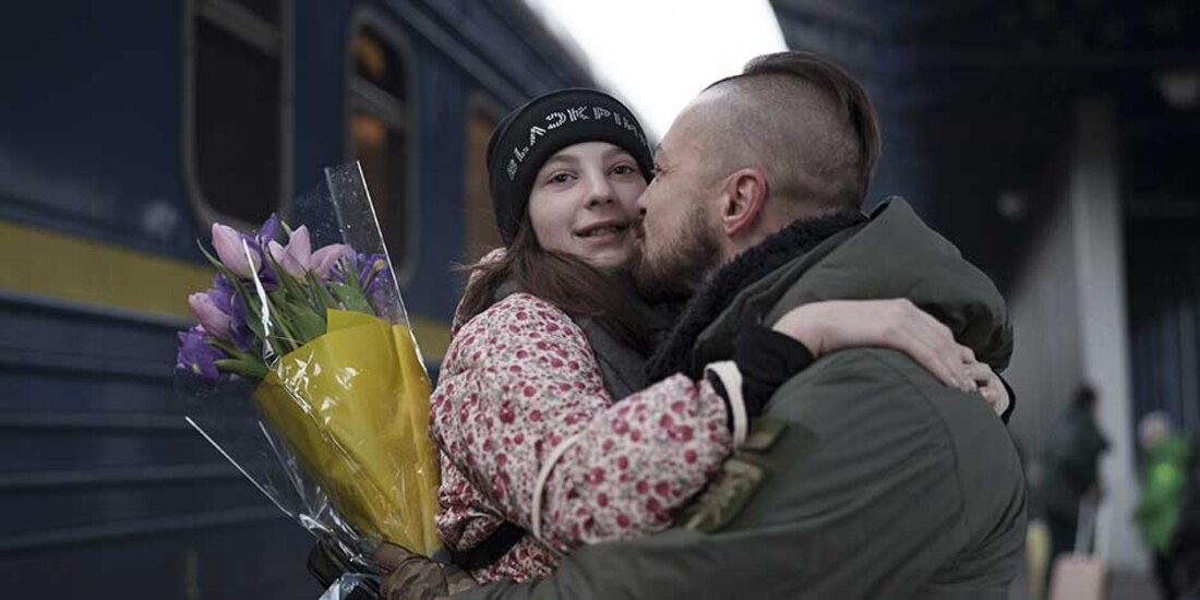 Mykyta, todavía en su uniforme, sostiene firmemente un ramo de rosas rosas mientras espera en la plataforma 9 a que su esposa Valeriia llegara de Polonia.