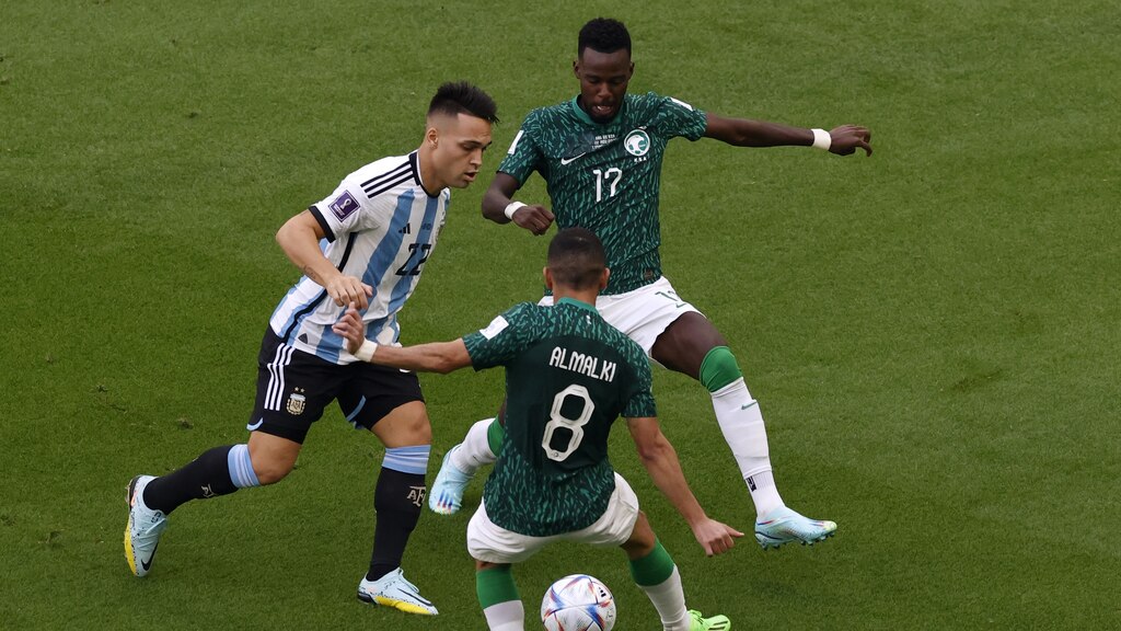 Lautaro Martínez, de Argentina, pelea el balón con Abdulellah Al-Malki y Hassan Tombakti, de Arabia Saudita, en el Mundial Qatar 2022.