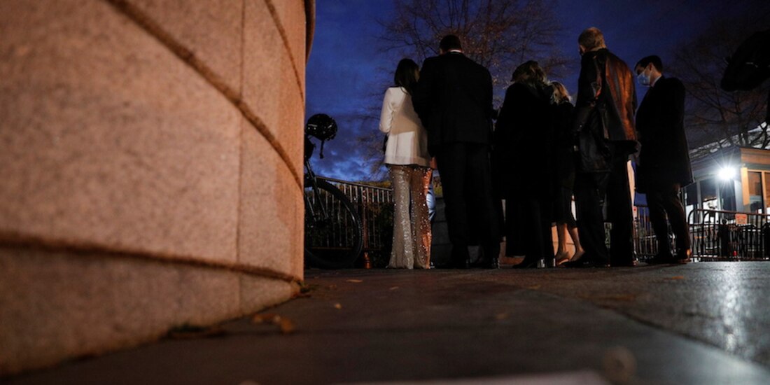 Un cubrebocas yace en el suelo junto a invitados que esperan para asistir a una fiesta, en Washington.