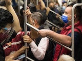 Un joven con cubrebocas y careta mira su celular en el Metro