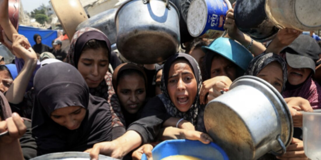 Gazatíes esperan alimentos de un comedor comunitario en Gaza, ayer.