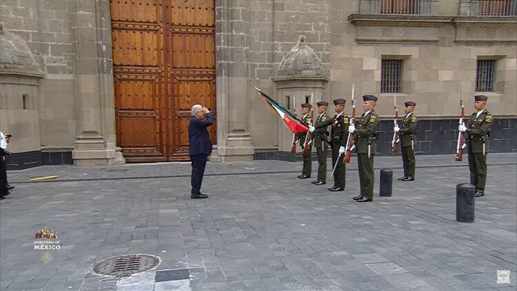 AMLO saluda a la bandera mexicana.