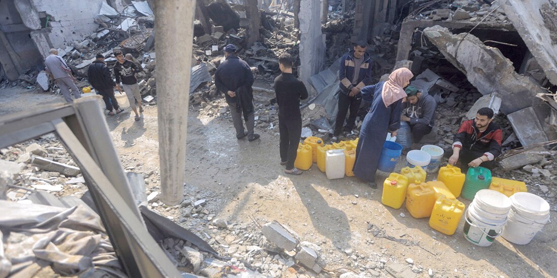Palestinos colectan agua en una vivienda destrozada por un ataque israelí, ayer, en Jabalia.