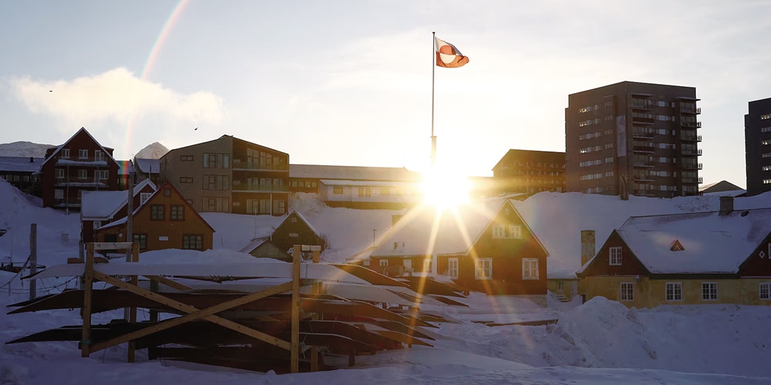 El sol sale detrás de la bandera de Groenlandia en el antiguo puerto de Nuuk, Groenlandia, el 5 de febrero de 2025.