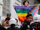 Manifestante con la bandera LGBT+ cerca de la policía turca antidisturbios que impide el Pride en Estambul.