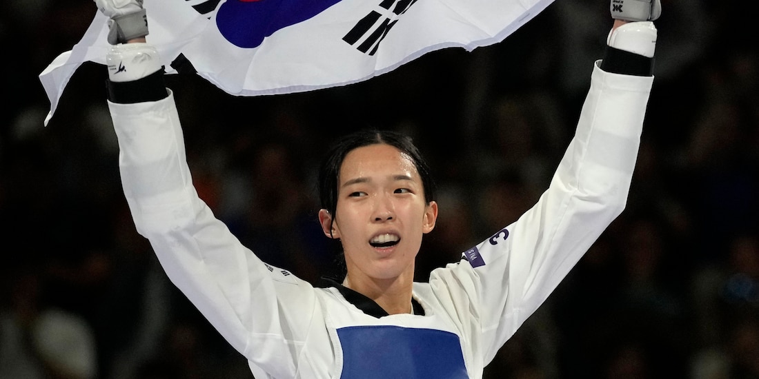 Kim Yujin sostiene la bandera de su país, ayer, después de su victoria.
