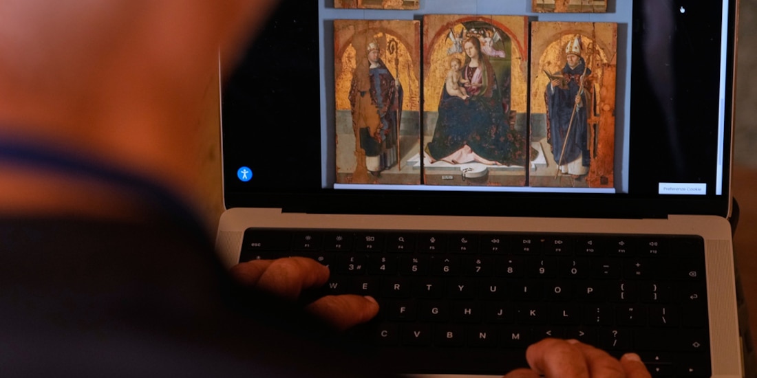 Fotografía ilustrativa de una persona mirando el sitio web del museo de Messina, donde se aprecia la imagen de una obra del pintor renacentista Antonello de Messina, con los paneles robados.