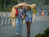 Dos personas en la calle se cubren con lo que pueden de la intensa lluvia
