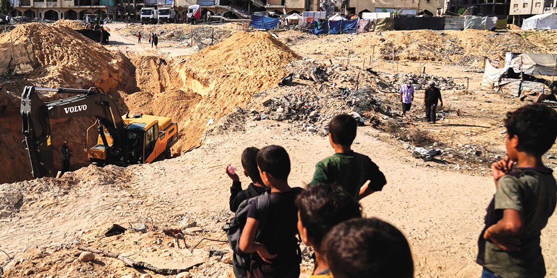 Palestinos observan cómo trabajadores egipcios buscan cuerpos de rehenes, ayer.