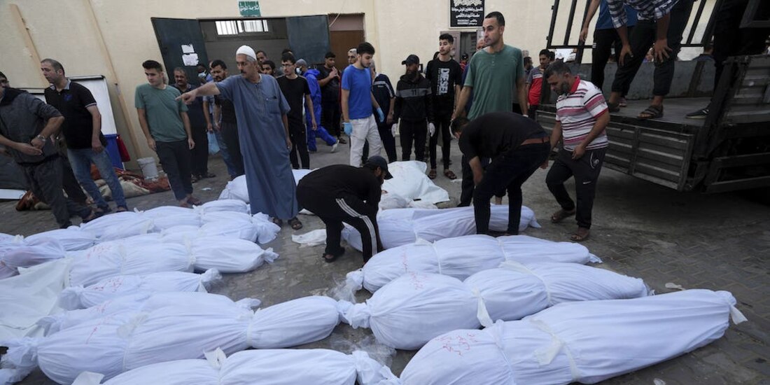 Residentes palestinos caminan entre decenas de cadáveres que saturan las morgues por nuevos bombardeos, ayer.