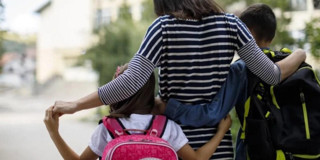 Una madre con sus hijos, antes de entrar a la escuela, en foto de archivo.