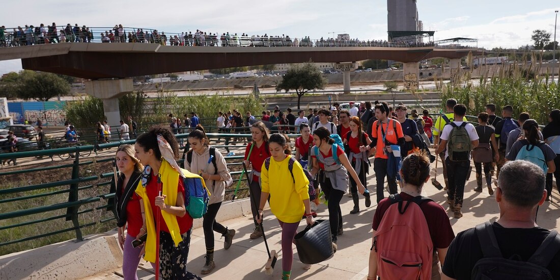 Cientos de personas cruzan el puente de Valencia para ayudar como voluntarios en las áreas afectadas, ayer.