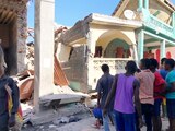 People stand in front of collapsed buildings following an earthquake in Jeremie, Haiti August 14, 2021, in this picture obtained from social media. Courtesy of TWITTER @JCOMHaiti/ via REUTERS ATTENTION EDITORS - THIS IMAGE HAS BEEN SUPPLIED BY A THIRD PARTY. MANDATORY CREDIT. MUST NOT OBSCURE LOGO
