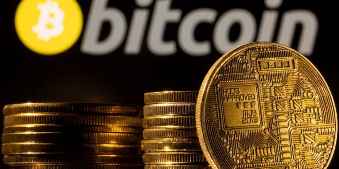 Una representación de la criptomoneda se ve frente al logotipo de Bitcoin.