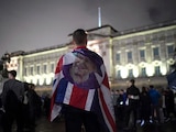 Un joven porta una bandera del Reino Unido con la cara de la reina Isabel II, tras su fallecimiento este jueves.