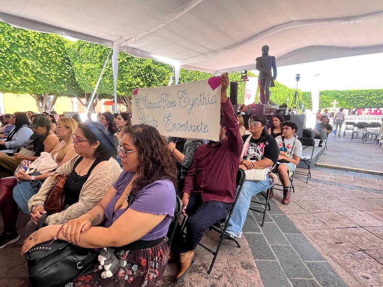 Dos personas sostienen una manta bordada con la leyenda: “Justicia para Cynthia. Hasta encontrarte” durante el conversatorio con Vivir Quintana en el Hay Festival Querétaro