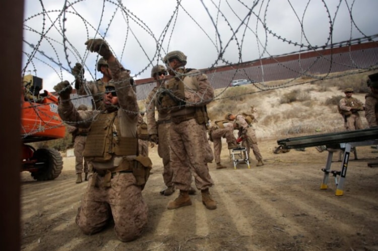 Elementos de Estados Unidos ajustan el alambre de púas a lo largo de la cerca principal en la frontera norte entre México y Estados Unidos.