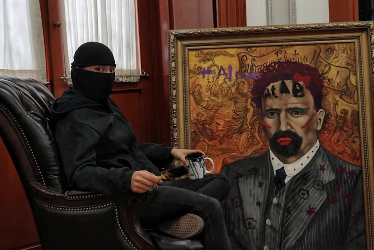 La activista que intervino el cuadro de Madero posa junto a la obra terminada.