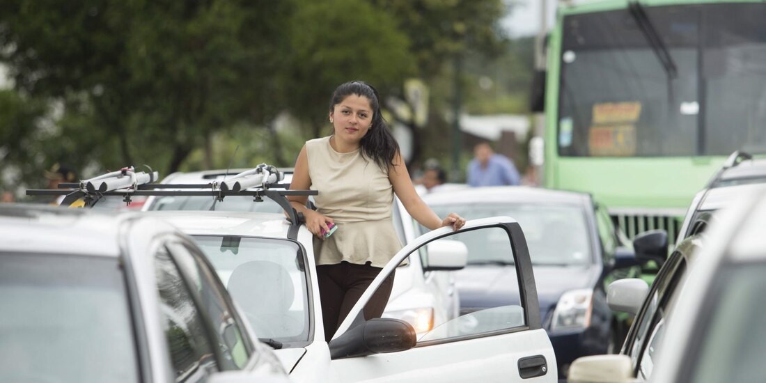 La imagen muestra a una conductora en calles de la CDMX, con la puerta de su vehículo abierta 