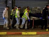 Personal médico y rescatistas israelíes evacuan un cadáver de la escena de un ataque en el que hombres armados mataron a personas en una calle principal de Hadera, Israel.