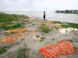 A municipal worker walks past shallow sand graves, some of which are suspected to have died from COVID-19, on the Ganges riverbank in Phaphamau, on the outskirts of Prayagraj, India, June 25, 2021. REUTERS/Ritesh Shukla