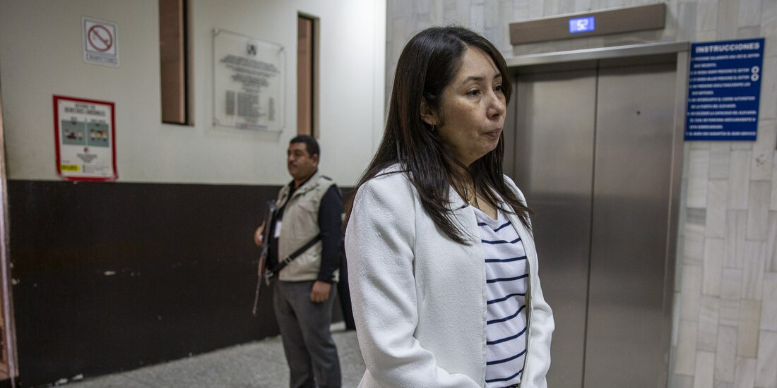 Erika Aifán en imagen de archivo mientras hablaba con periodistas, escoltada por un guardespaldas en la sala judicial en Guatemala.