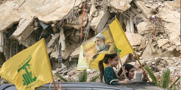 LIBANESES desplazados circulan por calles de Dahiyeh con banderas de Hezbolá y fotos de su líder, Naim Qassem, ayer.
