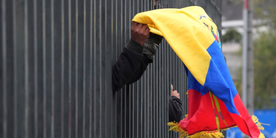 Un manifestante indígena lleva una bandera ecuatoriana dentro de la Casa de la Cultura en Quito mientras policías fuerzan a los manifestantes a quedarse adentro durante una protesta contra el gobierno del presidente Guillermo Lasso el 24 de junio del 2022