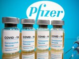 Fotografía tomada el 31 de octubre de 2020 en la que se ven frascos con etiquetas que dicen "COVID-19/Vacuna contra el coronavirus/Solo inyección" y una jeringa médica frente al logotipo de Pfizer.
