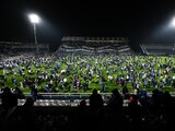 Aficionados de Gimnasia y Esgrima saltan a la cancha luego de que gases lacrimógenos inundaran el estadio durante su juego como locales contra Boca Juniors en la liga de Argentina.