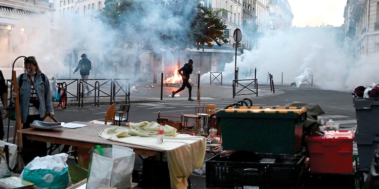 UN MANIFESTANTE corre entre gases lacrimógenos durante los enfrentamientos entre manifestantes y policías en París, ayer.
