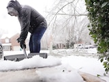Una imagen de AP en la que se muestra a una persona barriendo la grandes cantidades de nieve, ayer.