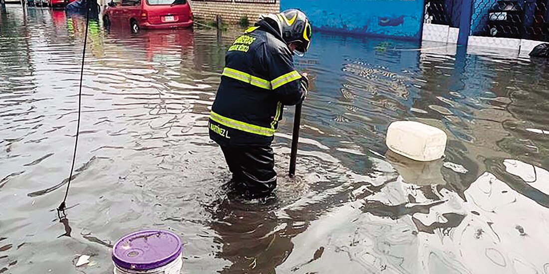 Un bombero destapa una coladera en Iztapalapa tras la lluvia, el martes.
