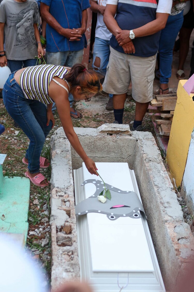 La madre de Aitana coloca una mantarraya de fomi y una flor blanca sobre el ataúd de su hija, antes de ser enterrada.
