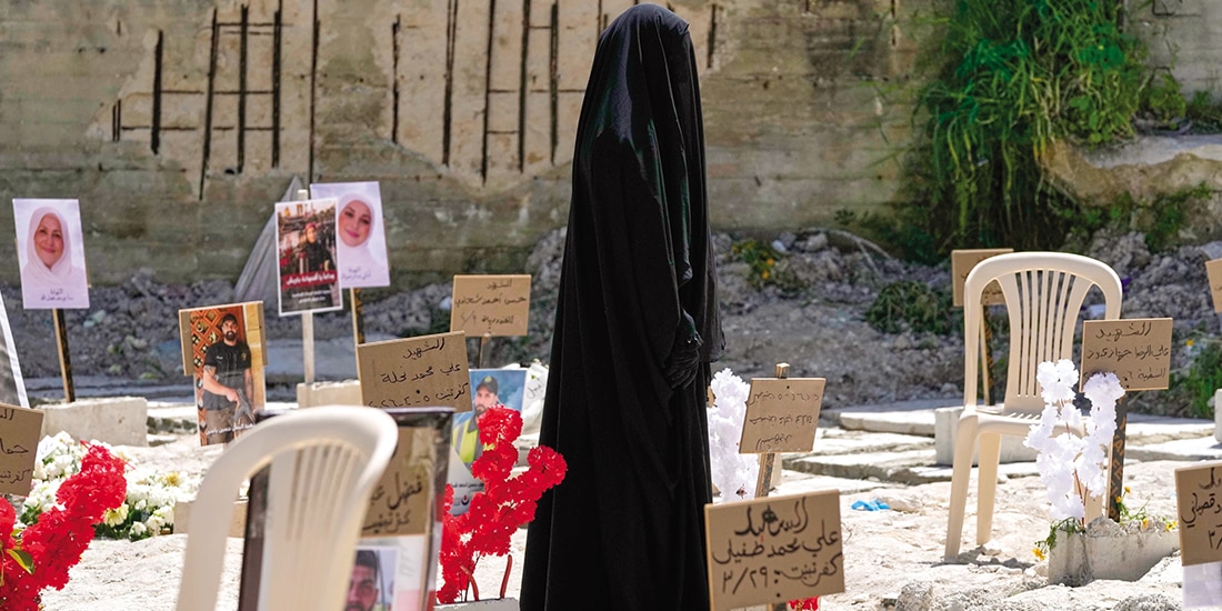 Una mujer con burka camina por una fosa
común, ayer