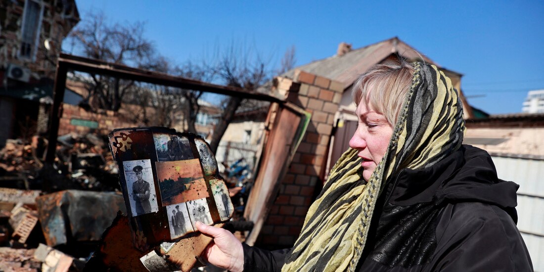Una mujer inspecciona sus pertenencias en las ruinas de su casa que fue atacada en un ataque militar, en medio de la invasión rusa en Ucrania, en Kiev.