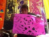 Una mujer vende papel picado en el mercado de la Merced para la celebración del Día de Muertos