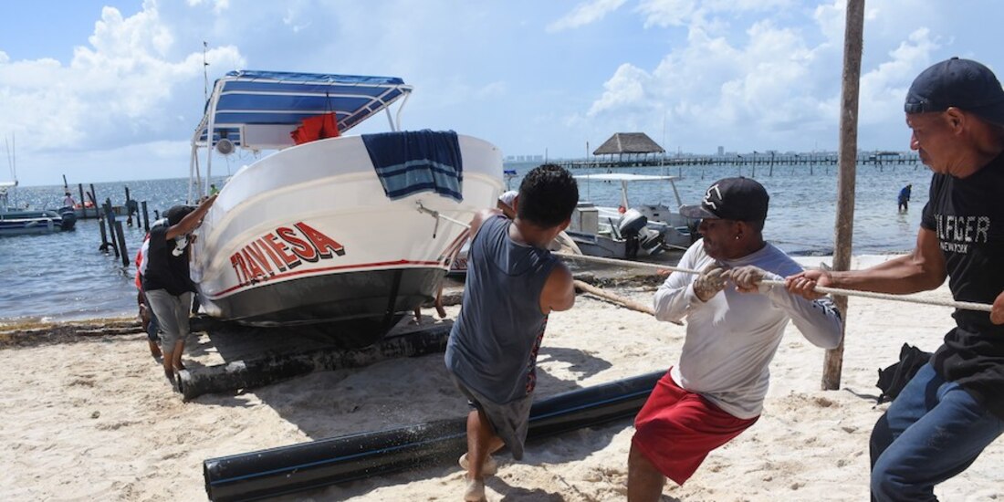 Pescadores retiran sus embarcaciones del mar, horas antes de la llegada de Grace, que este jueves impactó a la Península de Yucatán.