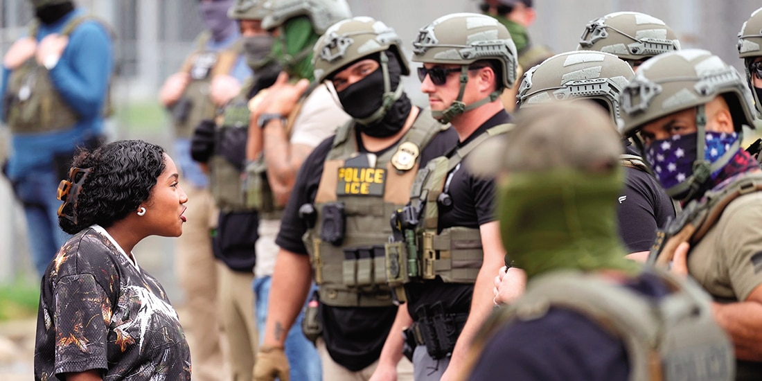 Manifestante habla con agentes enmascarados en Newark