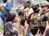 Manifestante habla con agentes enmascarados en Newark
