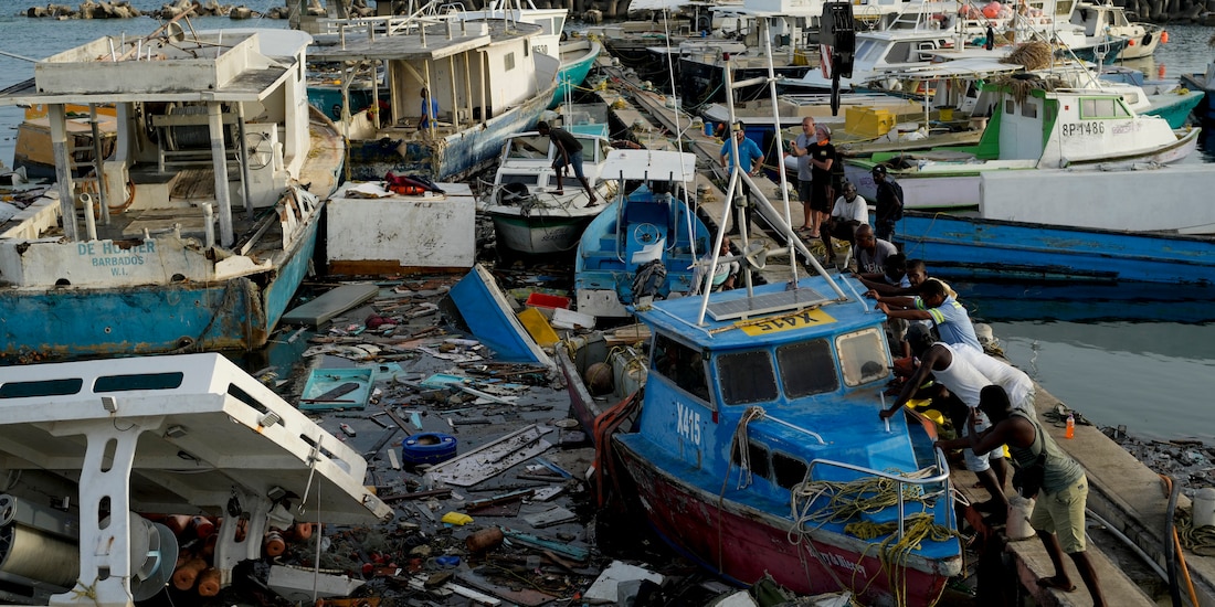 Residentes de Santa Lucía intentan desatascar un barco en un puerto de Barbados, ayer.