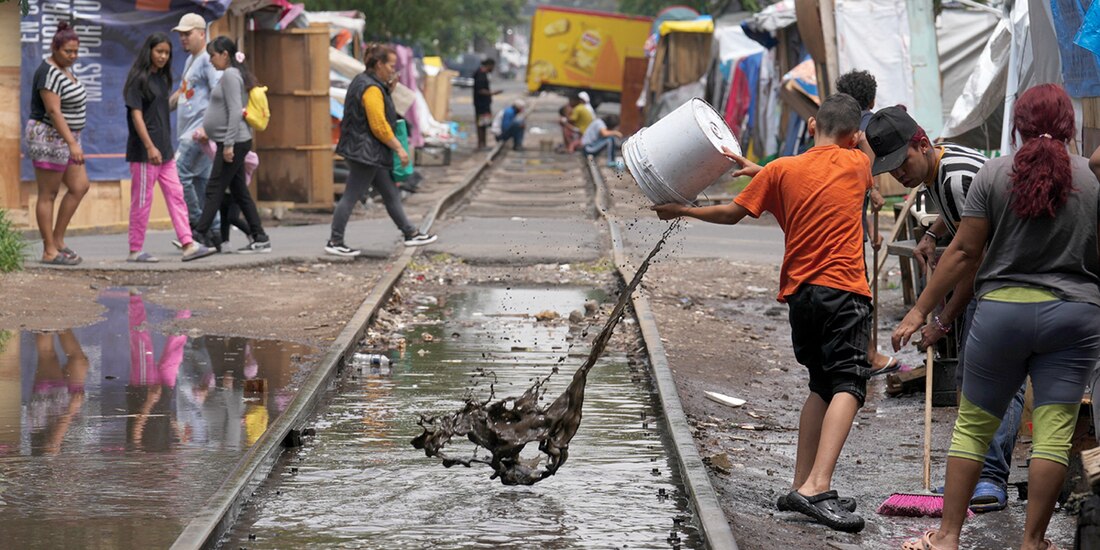 Migrantes en un campamento de la colonia Vallejo sacan el agua acumulada por las fuertes lluvias de los últimos días, el pasado jueves 18 de julio.
