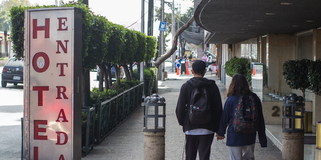 Dos jóvenes caminan frente a un hotel ubicado en Tlalpan.